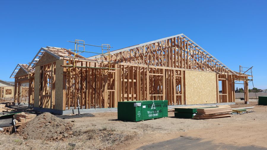 A new single-family home under construction with its wooden roof and wall framing exposed